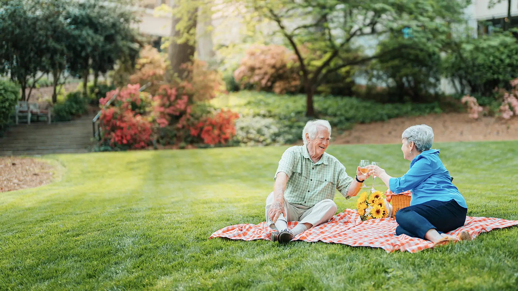 A senior couple picnics on the ground in a courtyard