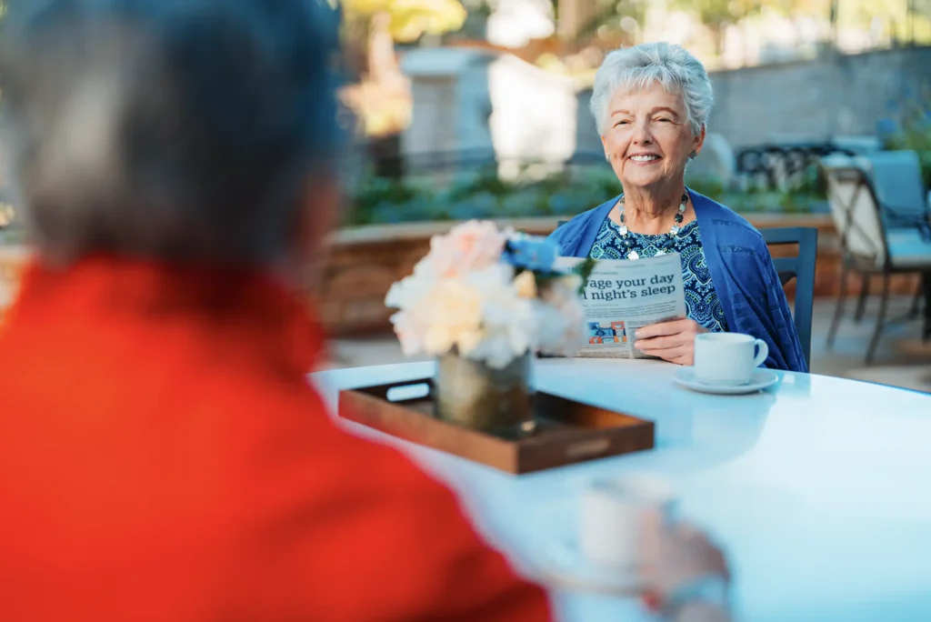 Resident enjoying a cup of coffee and reading the newspaper outside at Canterbury Court.